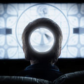 Egy ember ül a TV előtt, a fején egy hatalmas lyuk tátong